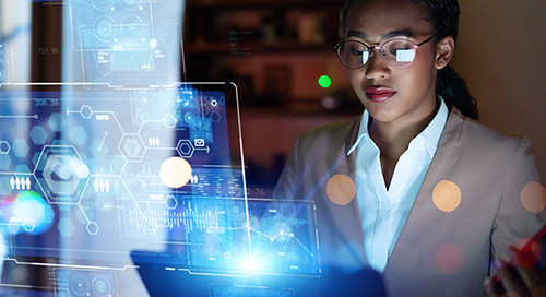 A professional woman in a brown coat holds a smartphone and works on a hypermodern interactive desktop in a dimly lit office setting