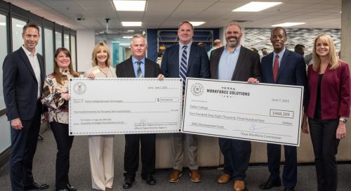 A photo of Gainwell staff members and Dallas College leadership in business attire holding two large novelty checks symbolizing secured grants