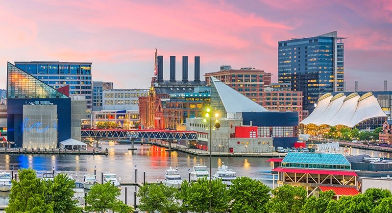 The coastal skyline of Cleveland at dusk, with boats in the foreground and the pink sky in the background
